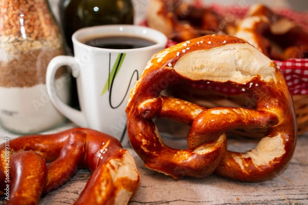 Fototapeta Brezel und Kaffee - zwei Brezeln auf einem gedeckten Tisch mit einer Tasse Kaffee - Salzbrezelbrezel - Salz