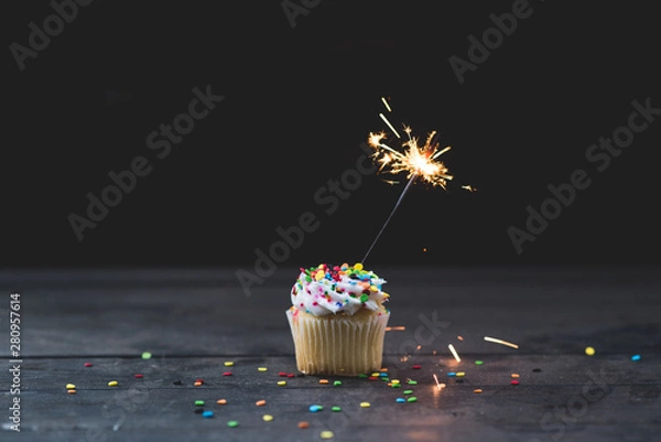 Fototapeta Pojedyncza babeczka z brylantem zwieńczona lukrem waniliowym i kolorowym konfetti