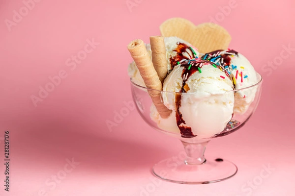 Fototapeta scoops of sundae ice cream in glass bowl with chocolate sauce, strewed sprinkles and cookies on pink background