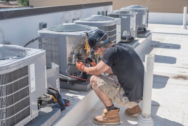 Fototapeta Hvac technician checking controls on a condenser