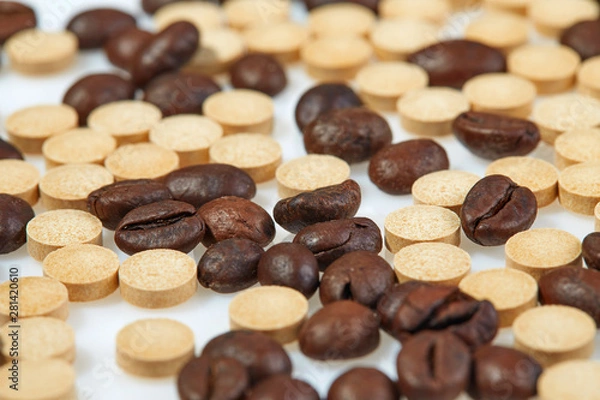 Fototapeta Coffee beans mixed with caffeine tablets are scattered on a light surface. Horizontal