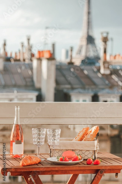 Obraz Paris luxury lifestyle. Pink wine, two glasses, traditional french bakery products - baguettes, macaron, croissant and strawberries on a balcony with a view on rooftops