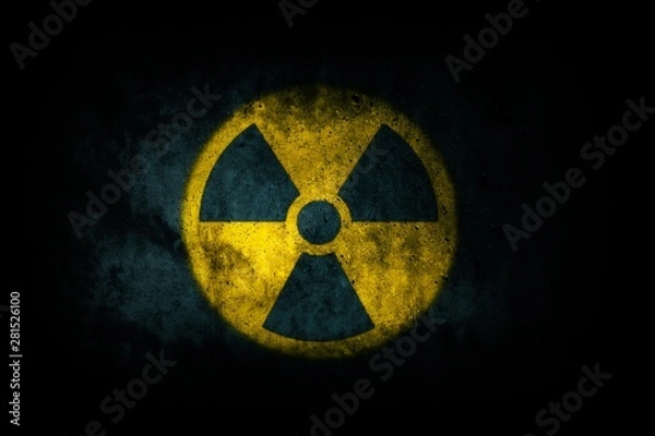 Fototapeta Nuclear energy radioactive (ionizing atomic radiation) round yellow symbol shape painted on massive concrete cement wall texture dark background. Nuclear radiation or radioactive alert warning danger.