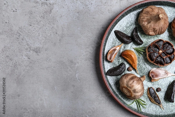Fototapeta Plate with black garlic on grey table, top view. Space for text