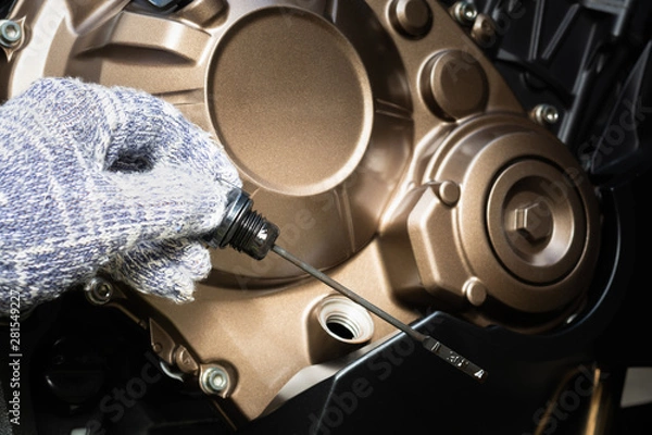 Obraz Hand of technician wearing cloth gloves check lubricant engine oil level motorcycle bigbike. maintenance motorcycle concept in garage or check before you travel.