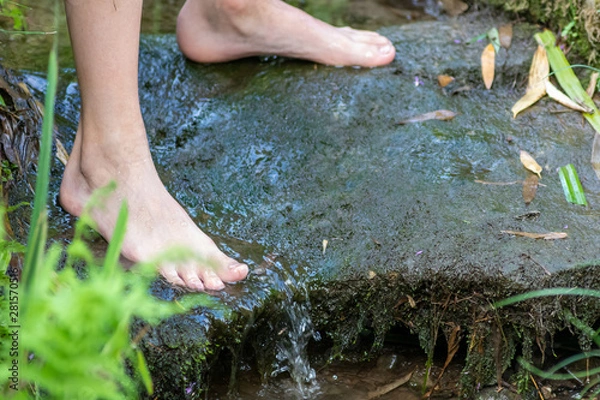 Fototapeta Kind kühlt seine nackten Füße in kaltem frischem Quellwasser eines kleinen Baches im Sommer und genießt die kühle Erfrischung