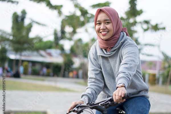 Fototapeta close up shot of hijab  woman in an outdoor hood with a bicycle posing in front of a camera on a bicycle