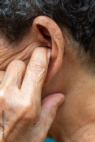 Fototapeta Senior woman putting index finger into her left ear, Grey curly hairs, Swimming pool background, Close up & Macro shot, Selective focus, Asian Body part, Healthcare concept, Symptom of hearing loss