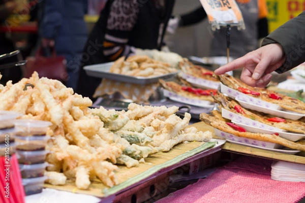 Fototapeta Busan, Korea, 12/22/2018 , Man pointing at some food on a street market in Busan.
