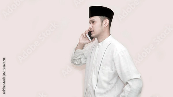Obraz side view portrait of an asian muslim man using smartphone taking a call