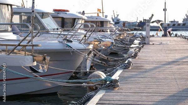 Fototapeta View on the swing moorings and pile moorings of the boats in the port. Moored small motorboats at the dock at summer time. Quays, wharfs, jetties, piers.