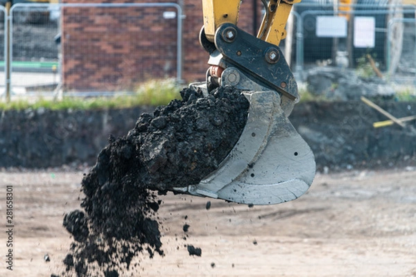 Fototapeta A digger and dump truck move dirt to make room for the foundations of the new Waverley School in Sheffield, South Yorkshire, UK