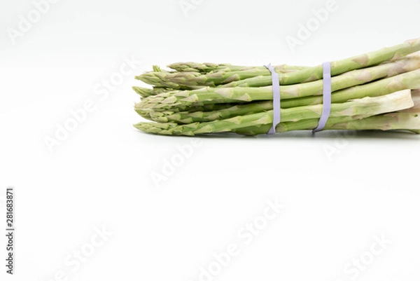 Fototapeta Asparagus surrounded by a medical tape on weighing scale for diets