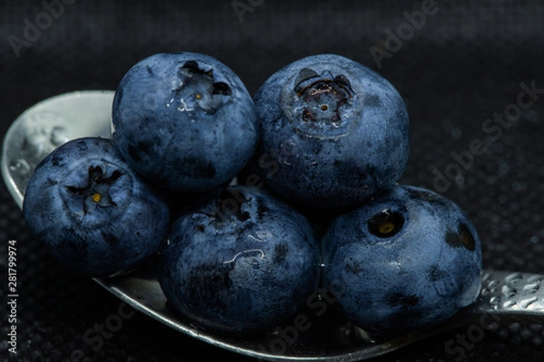 Obraz Blueberries Macro closeup photo of superimposed on top of each other and tiled in a teaspoon on a dark background glistening in drops of fresh water.