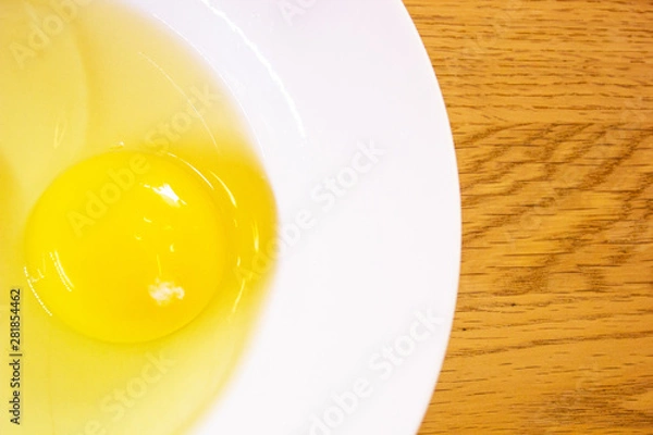 Obraz Close up One Yolk Egg On white Plate in Brown Wood Stripe Background