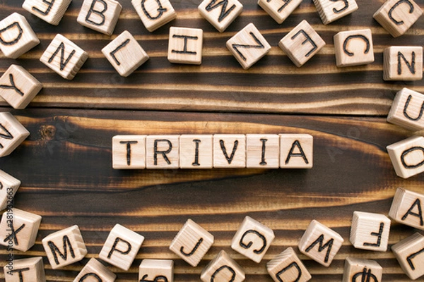 Fototapeta trivia - word from wooden blocks with letters, unimportant concept, random letters around, top view on wooden background