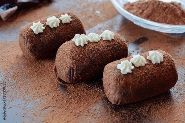 Fototapeta Delicious chocolate brownie as a potato form, Russian traditional dessert, on a dark desk and cacao powder on it, close up