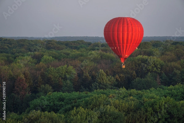 Obraz Red hot air balloon in the sky above the trees