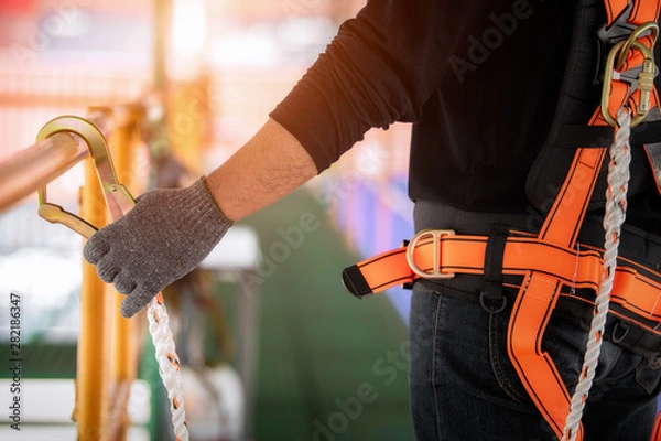 Fototapeta Construction worker wearing safety harness and safety line working high place at industrial.