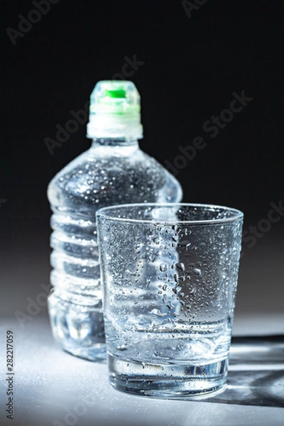 Obraz Glass of water with a bottle on table