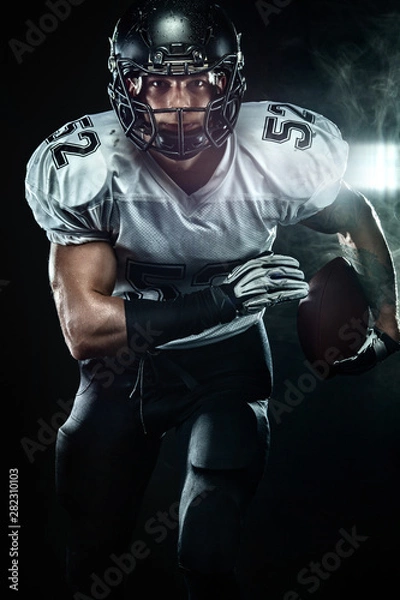 Fototapeta American football sportsman player in helmet on black background with smoke. Sport and motivation wallpaper.