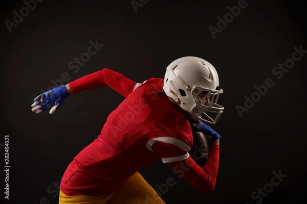 Fototapeta Photo of sporty woman running to right with rugby ball in helmet