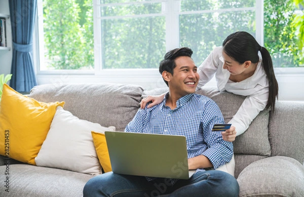 Fototapeta Happy Smiling Couple with Online Shopping Using Credit Card to Internet Shop on-line. Young couple with Laptop Computer and Credit Card buying online. Generation, relationship, modern technology.