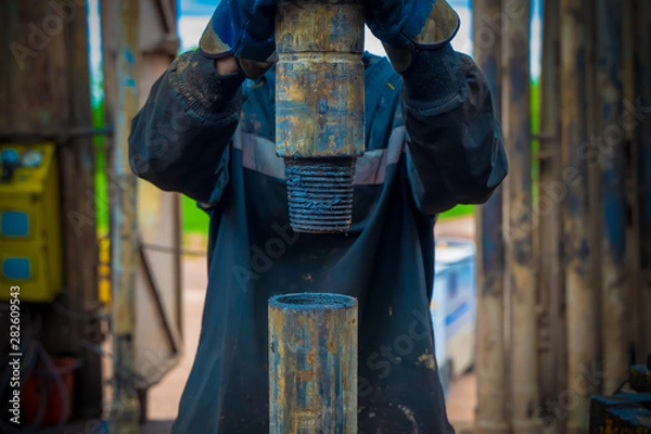 Fototapeta Offshore oil rig worker prepare tool and equipment for perforation oil and gas well at wellhead platform. Making up a drill pipe connection. A view for drill pipe connection from between the stands
