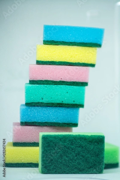 Obraz Different color sponges for washing dishes, staggered on top of each other close up on a white background