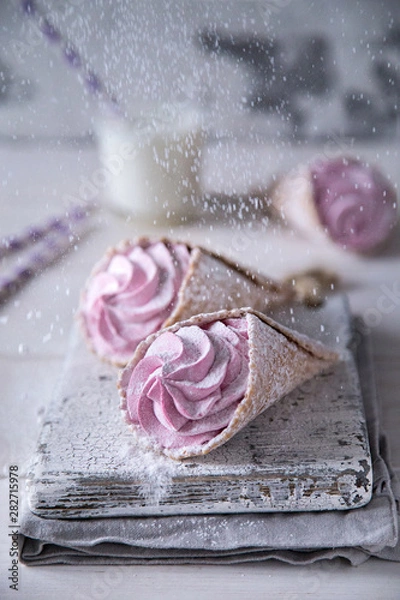 Fototapeta Ice-cream like pink handmade zephyr in waffle cones decorated snow sugar powder on light background with milk