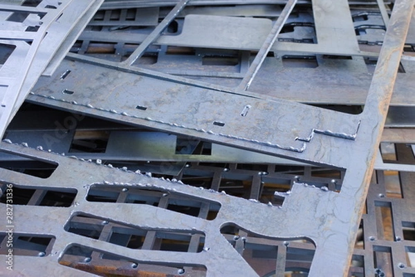 Fototapeta Perforated metal sheets after laser cutting lie on each other. Metalworking waste prepared for recycling.
