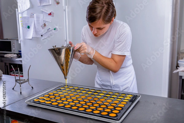 Obraz Pastry chef in the kitchen makes passion fruit confit. Cook pours passion fruit confit into the molds. Master class in the kitchen. The process of cooking. Step by step. Tutorial. Close-up