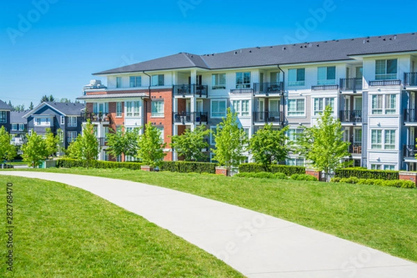 Obraz Betonowa ścieżka przez zielony trawnik przed budynkiem mieszkalnym