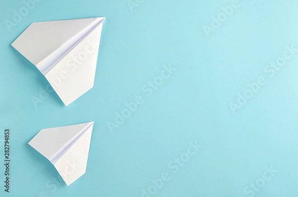 Fototapeta White paper planes on blue background composition.