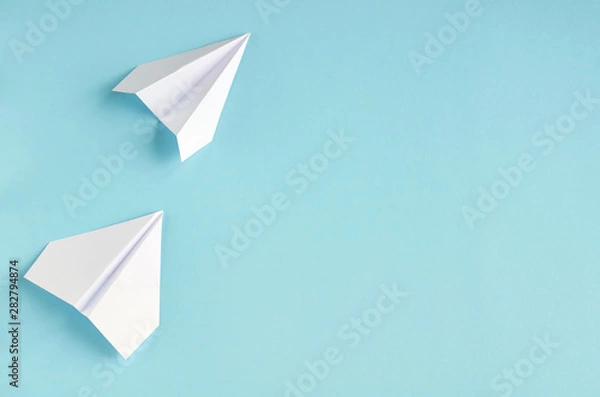 Fototapeta White paper planes on blue background composition.