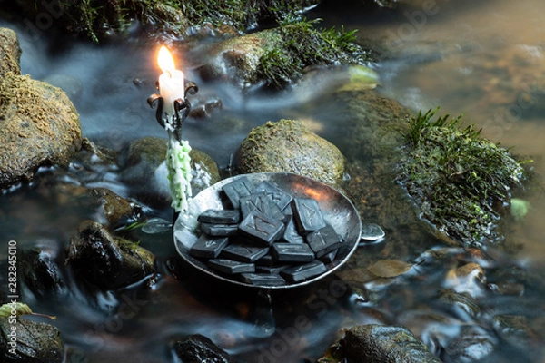 Fototapeta Norse Runes in a forged bowl with candle. In the evening  on the river