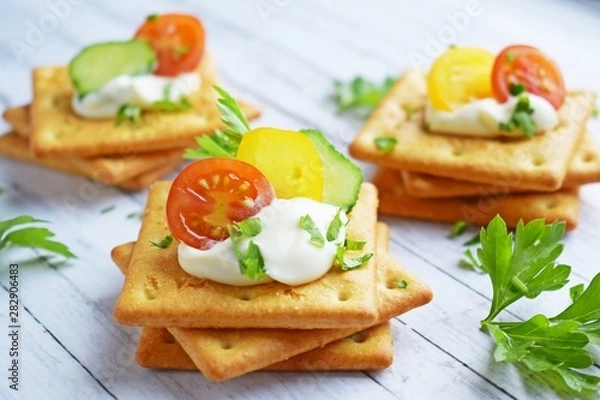Obraz Delicious crackers with cheese sauce and vegetables.Snack on wooden background.