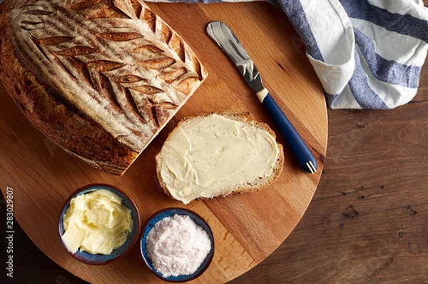 Fototapeta Artisan sourdough sliced toast bread with butter and pink himalayan salt on cutting board