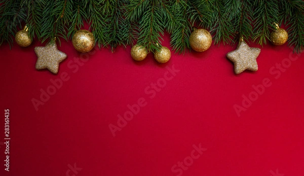 Fototapeta Christmas holidays composition on red background with copy space for your text. Christmas red decorations, fir tree branches on red background. Flat lay, top view, copy space.