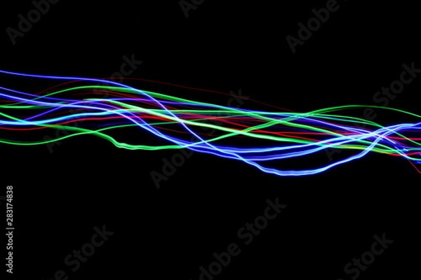 Obraz Long exposure, light painting photography.  Vibrant streaks of neon multi color against a black background.