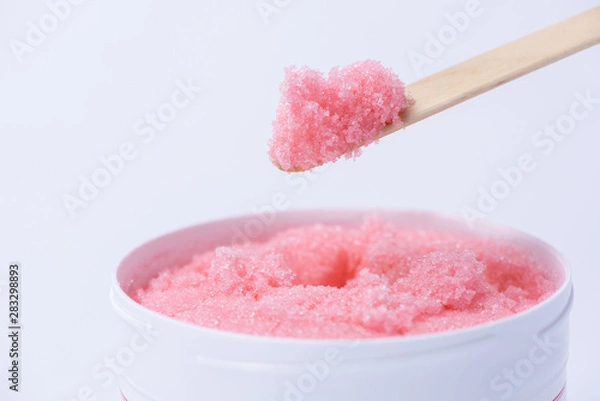 Fototapeta Pink sugar scrub with the smell of strawberries for the depilation process on a white background