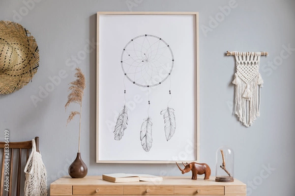 Obraz Stylish and bohemian concept of living room with mock up poster frame, chair, wooden desk, flowers in vase, macrame and elegant accessories. Modern interior design. Home decor. Template. Ready to use