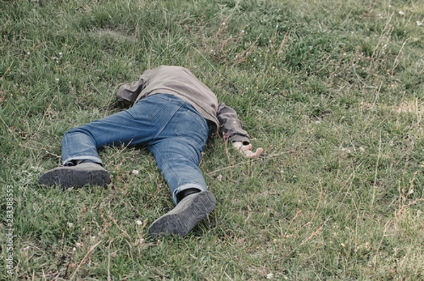 Obraz The corpse of a tramp in the grass. Criminal. Alcoholic intoxication. Killing a homeless man. dead body after lightning strike
