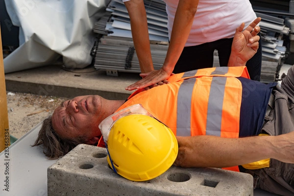 Fototapeta Cropped image of a paramedic's hands providing cardiopulmonary resuscitation (CPR) on a construction worker injured in an accident at work