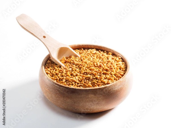 Fototapeta Fenugreek (Trigonella) in a wooden cup with a scoop on a white background