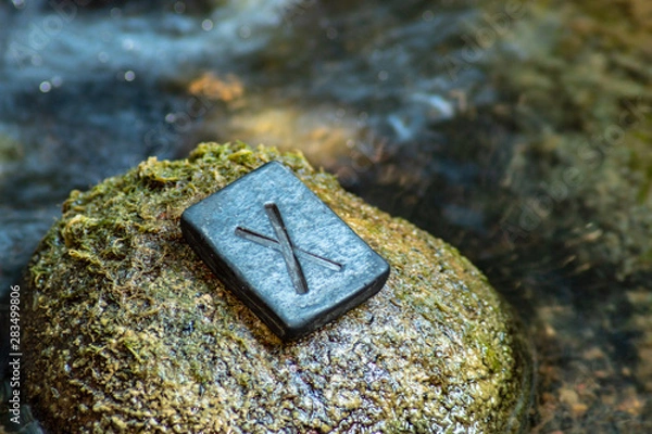 Fototapeta Norse rune Gebo (Gibu) on the stone and the evening river background. Gift, balance, harmony, giftedness. The rune is associated with the supreme Scandinavian God Odin.