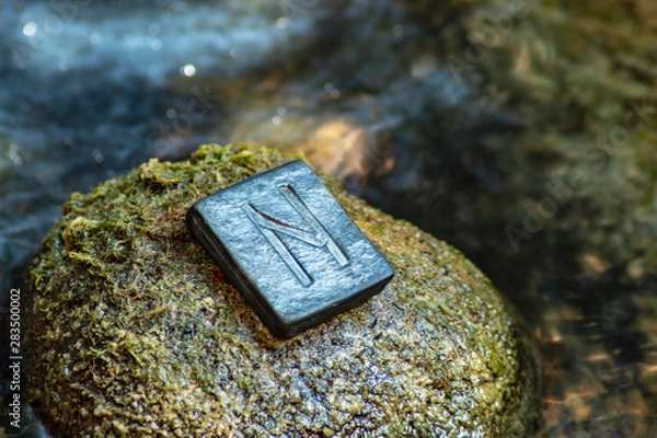 Fototapeta Norse rune Hagalaz (Hagal) on the stone and the evening river background. Excitement, shake, exit the comfort zone. Getting rid of old unnecessary patterns.