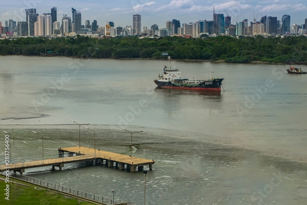Fototapeta view of placid dock in a Chao Phraya River, has cargo ships docked in the middle river And the back is green zone in Bang Krachao.