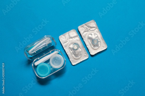 Fototapeta Blue color pair of contact lenses in blisters with blue contact lens case and tweezers on blue background