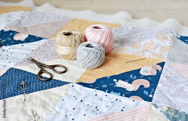 Fototapeta Hand stitch quilting process: cotton thread, needle and scissors on the table	